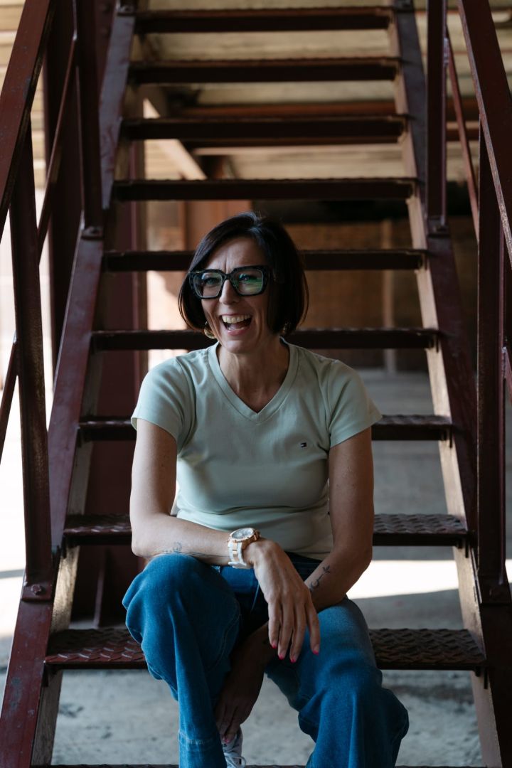 Claudia Bartsch sitzt lachend auf einer Treppe