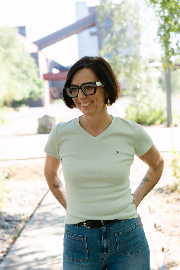 Claudia Bartsch steht lachend im Freien, die Hände in die Hüften gestützt